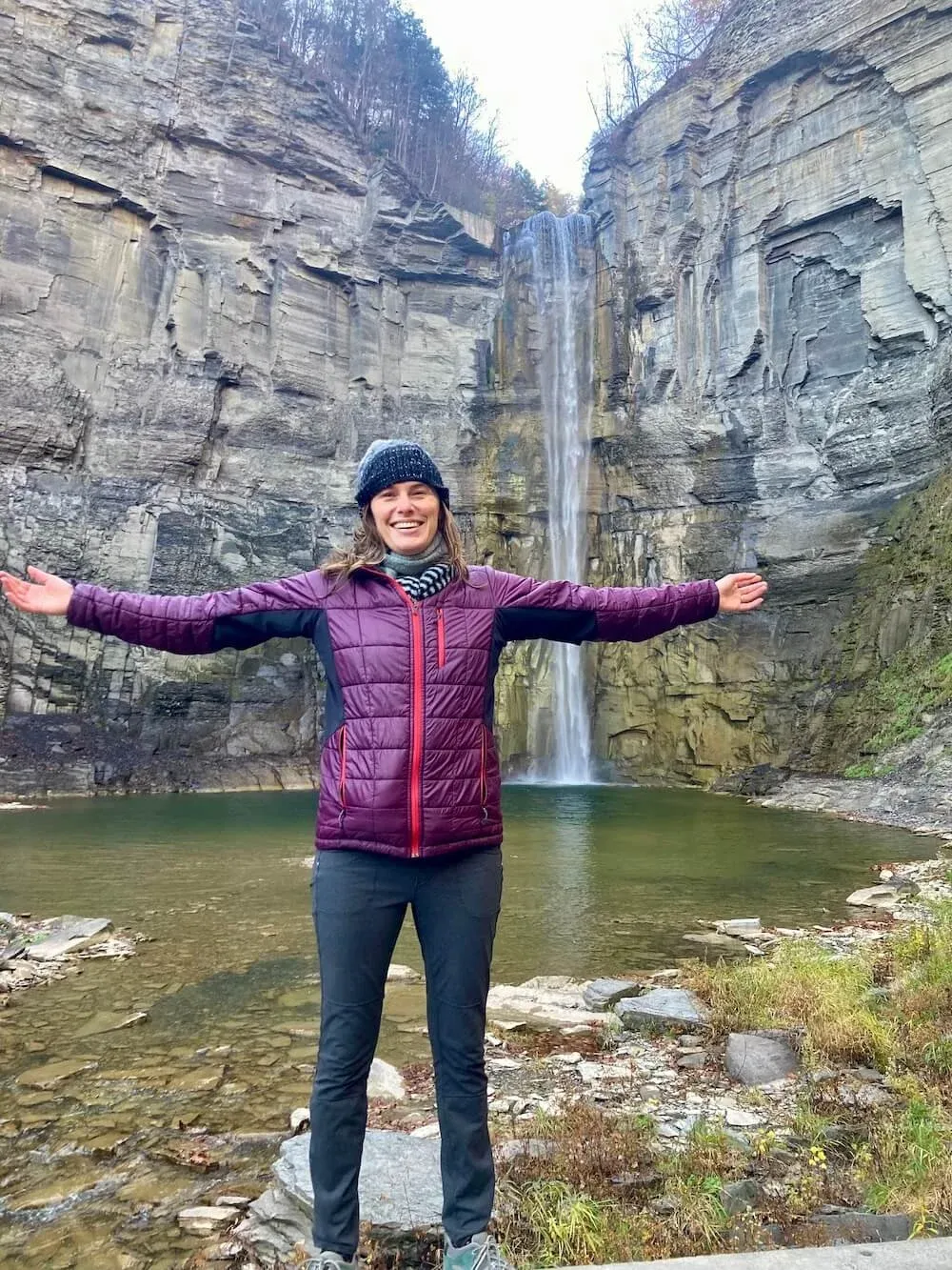 Laurie Buehler, MFT, therapist, arms open at Taughannock Falls in Ithaca, New York